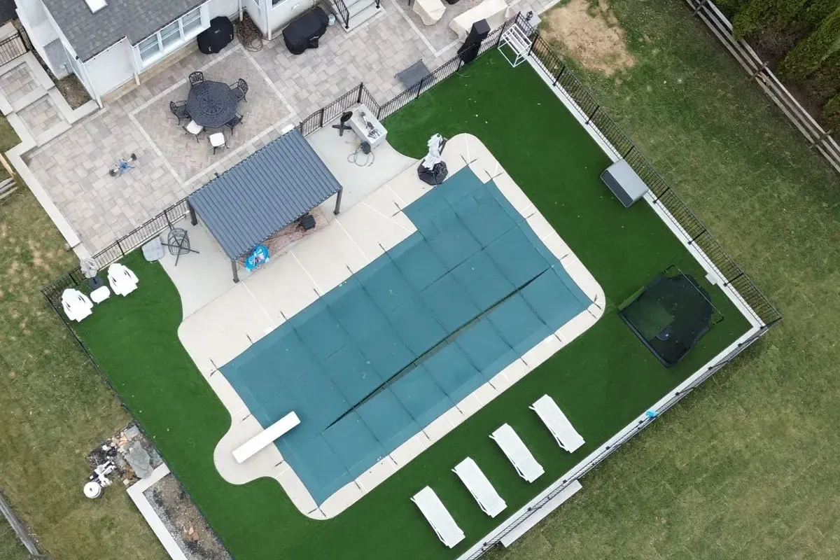 Artificial turf pool deck with pergola and paver patio aerial view Chester County PA