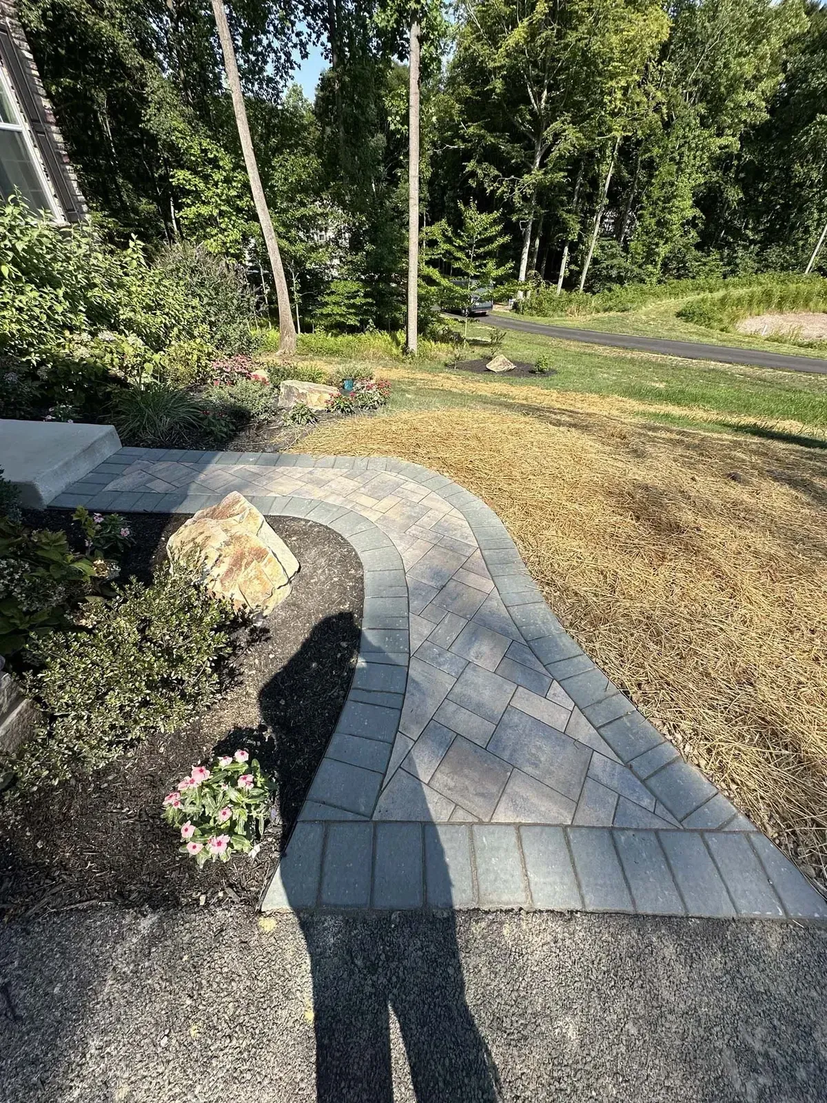 Curved front paver walkway with herringbone pattern and boulder accent in Chester County PA