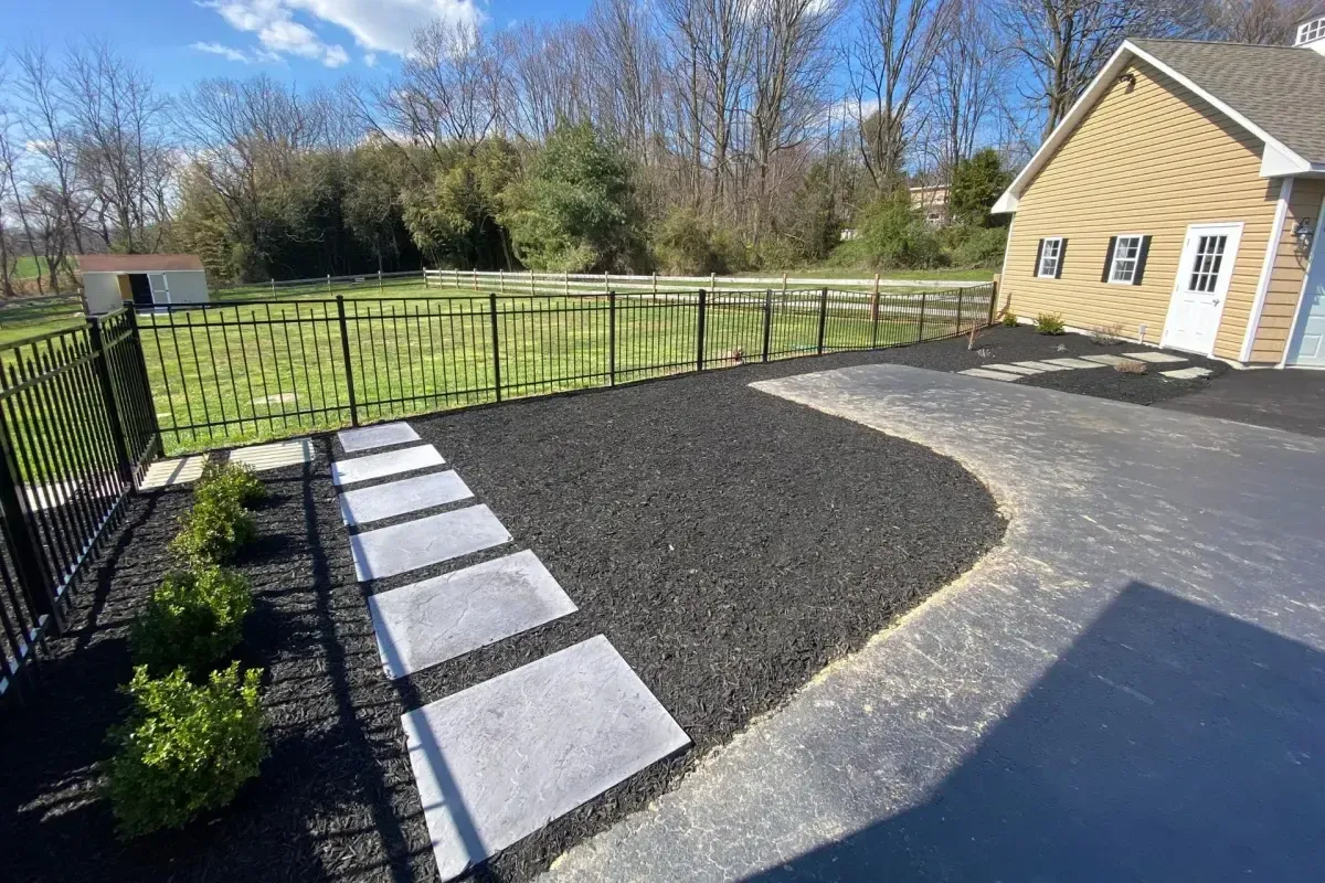 Modern large stepping stones in dark mulch with aluminum fencing in Chester County PA