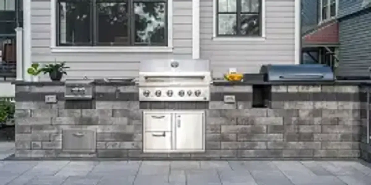 Custom outdoor kitchen island with grill and stone veneer on paver patio Chester County PA