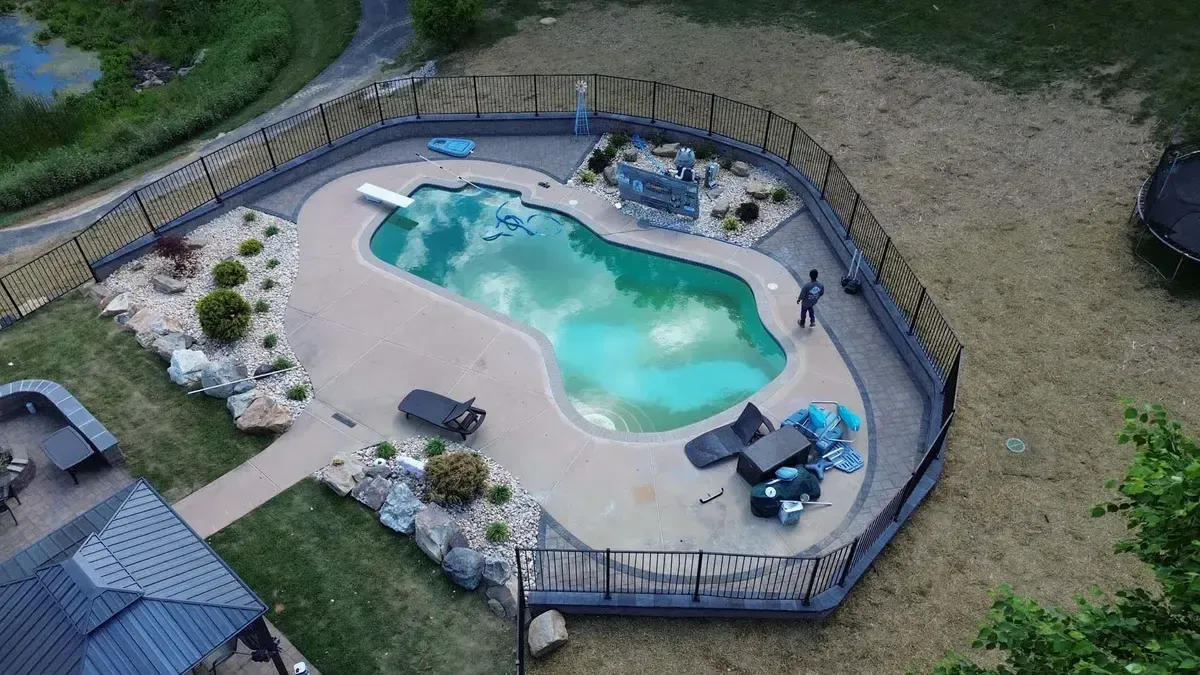 Aerial view of freeform pool deck with paver surround and boulder landscaping in Chester County PA