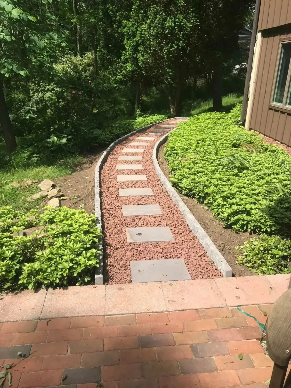 Curved stepping stone garden walkway with red gravel and lush plantings in Chester County PA