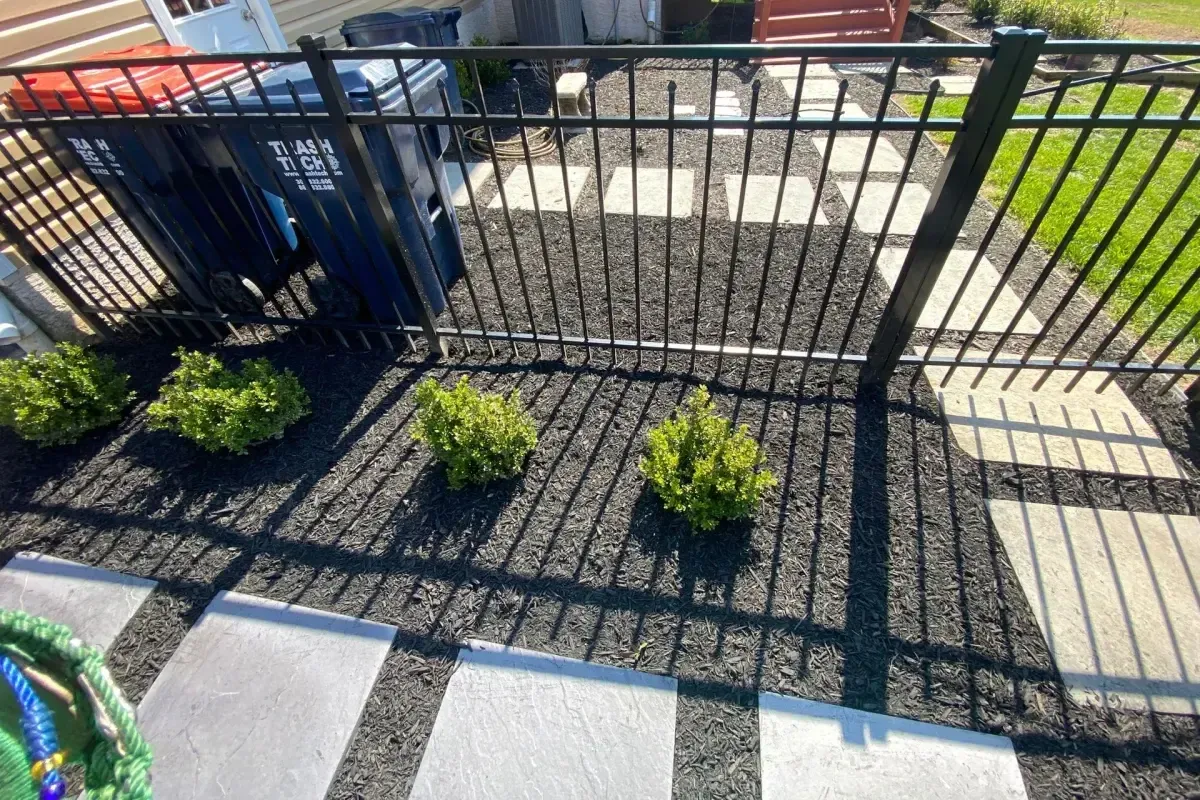 Stepping stones with boxwood shrubs and ornamental fencing landscape in Chester County PA